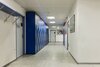Heller Korridor der BVS Business-School St. Gallen mit blauen Schließfächern und Kunstwerken an den Wänden.